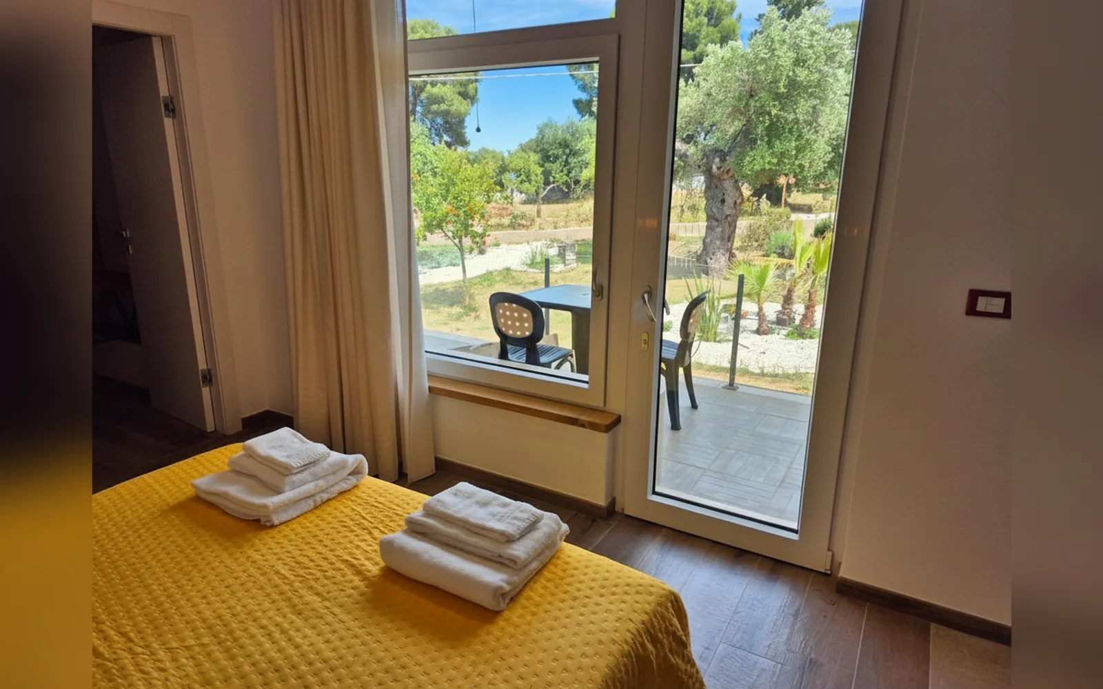 La portafinestra della camera aperta sul patio privato e sugli ulivi