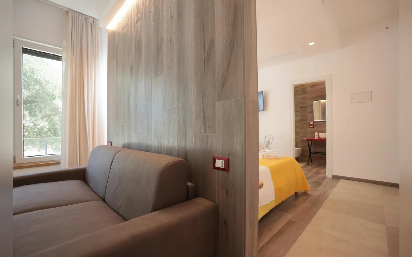 Il divano e il letto nella camera con la parete in legno