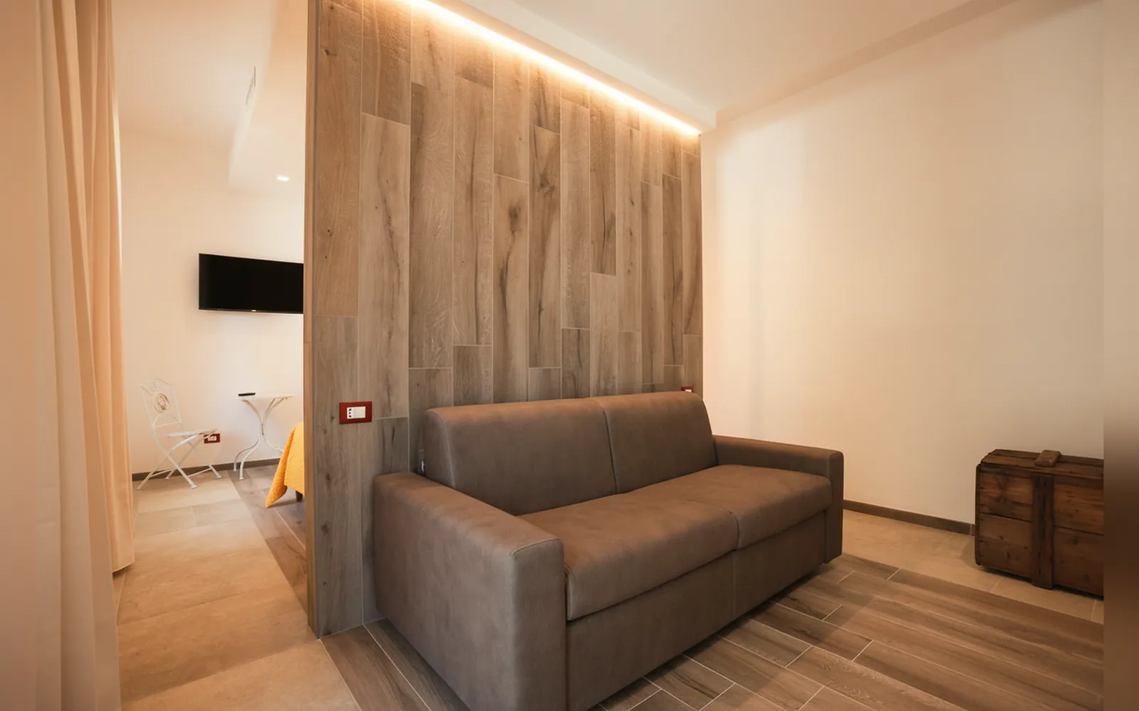 Il divano grigio accanto alla parete in legno