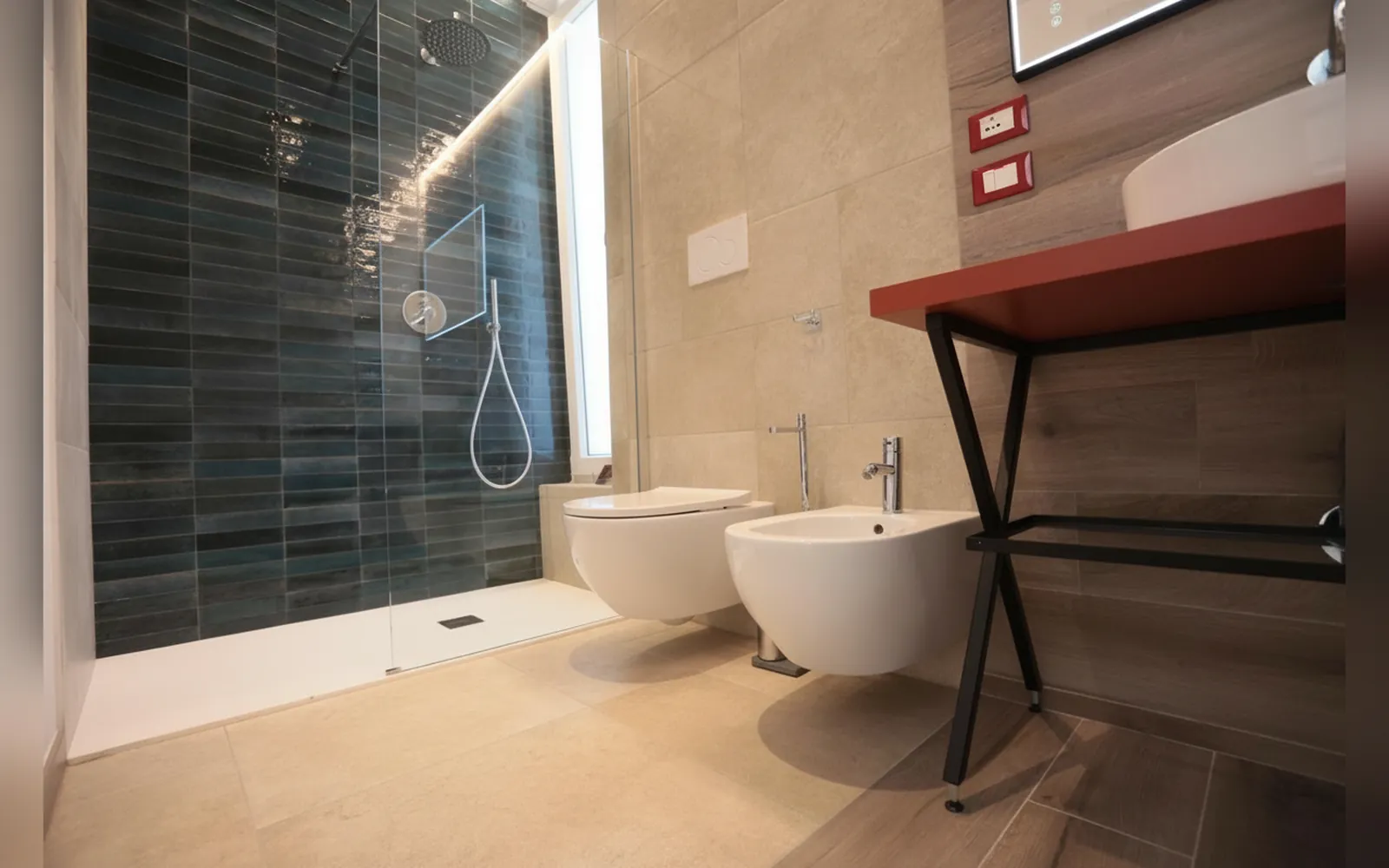 Il bagno privato con la doccia, il bidet e il piano rosso del lavabo